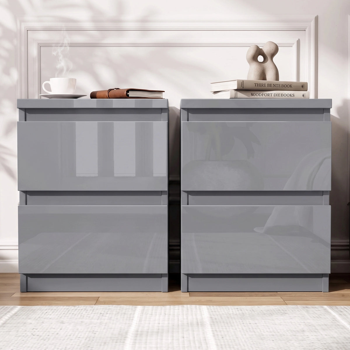 [Grey] Two modern nightstands with a glossy high-shine finish, shown side by side against a white paneled wall with decorative books and a coffee cup on top.