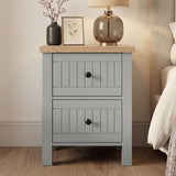 [Grey] Linra Painted 4 Piece Bedroom Furniture Set Grey bedside table with two drawers styled beside a bed with a smoked glass lamp, botanical print, and blossom stem vase