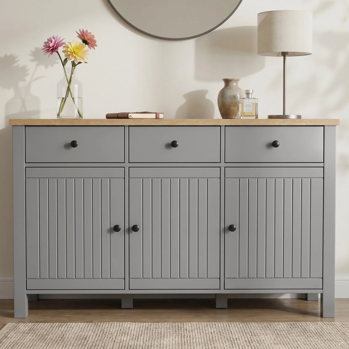 [Grey] Linra straight front detail showing three drawers, beadboard doors, oak-effect top, lamp, and vases