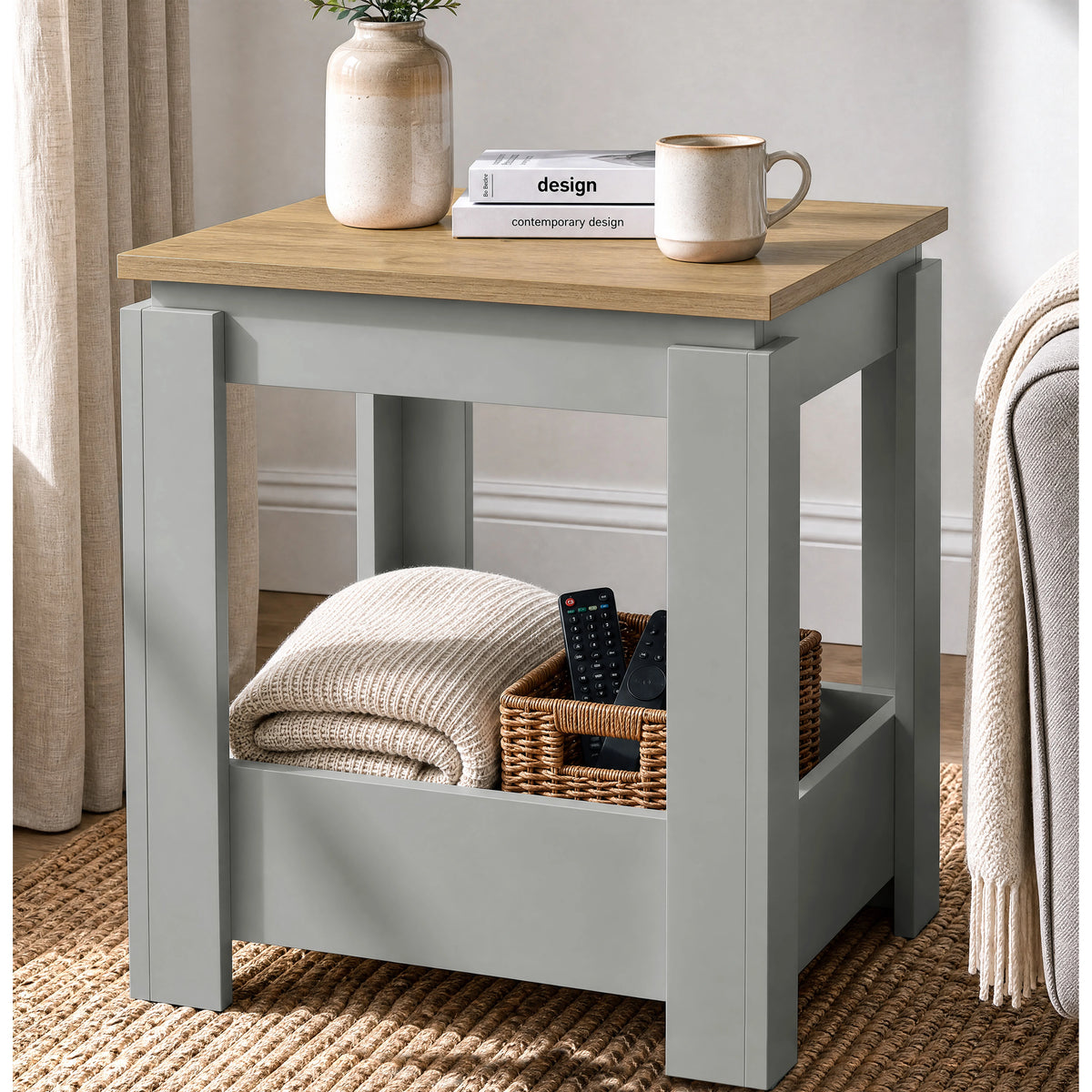 [Grey] Angled view of the square side table beside a sofa, with a folded throw and basket in the open lower storage