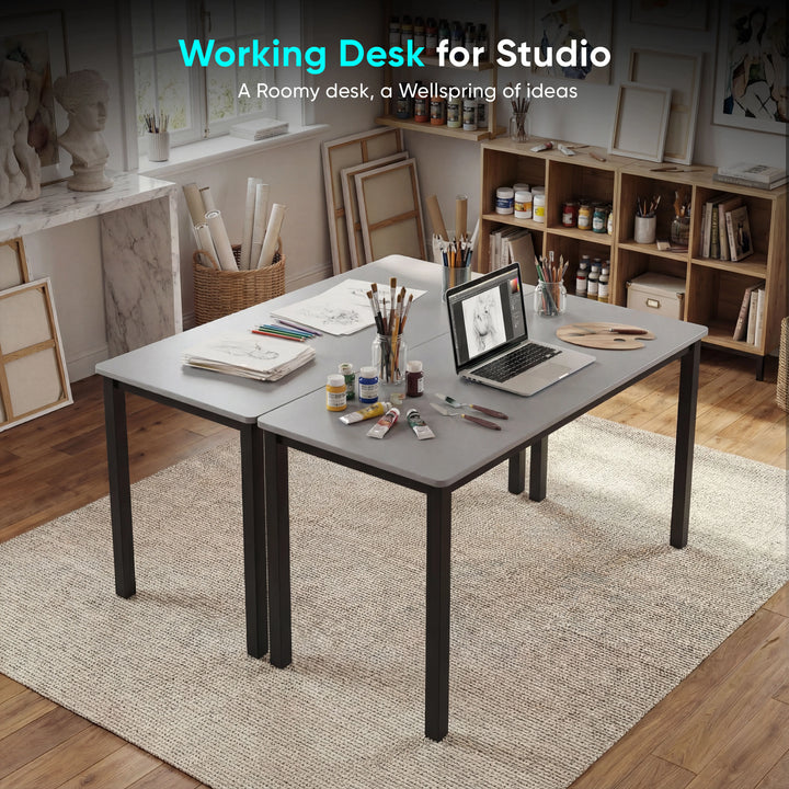 [100 X 50 cm] Office Desk arranged in artist studio with sketches, paint tubes, brushes in jars, pencils, and laptop on a soft area rug