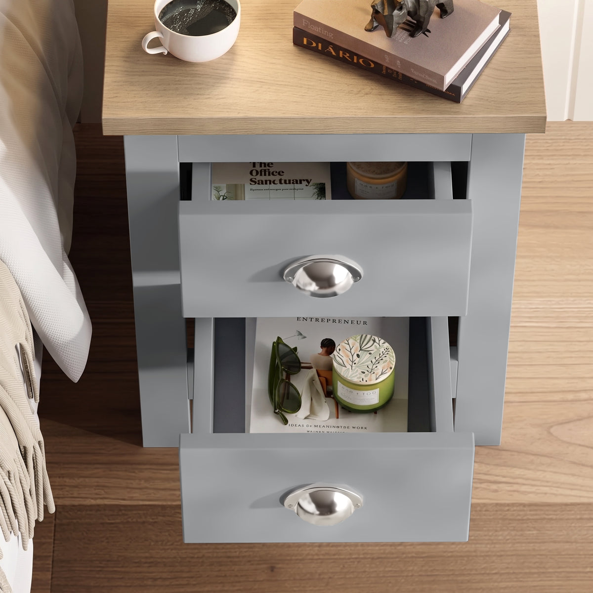 [Grey] Bedside table top view with both drawers open, books, mug, decor, wood surface, bed edge, and rug