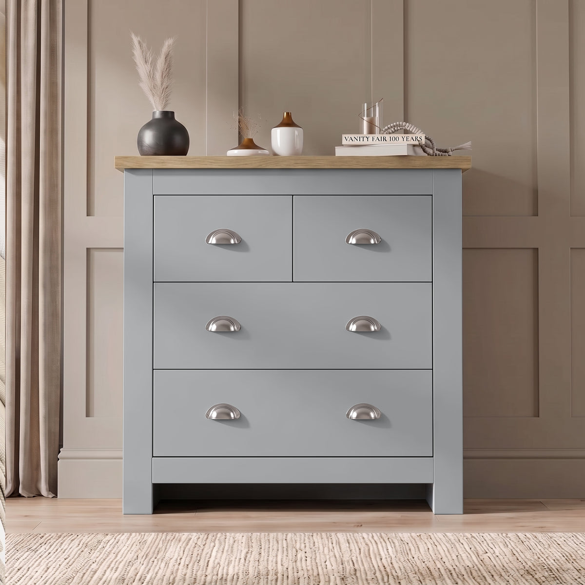 [Grey] Four drawer chest front view with oak top, chrome cup handles, pampas vase, books, and panelled wall