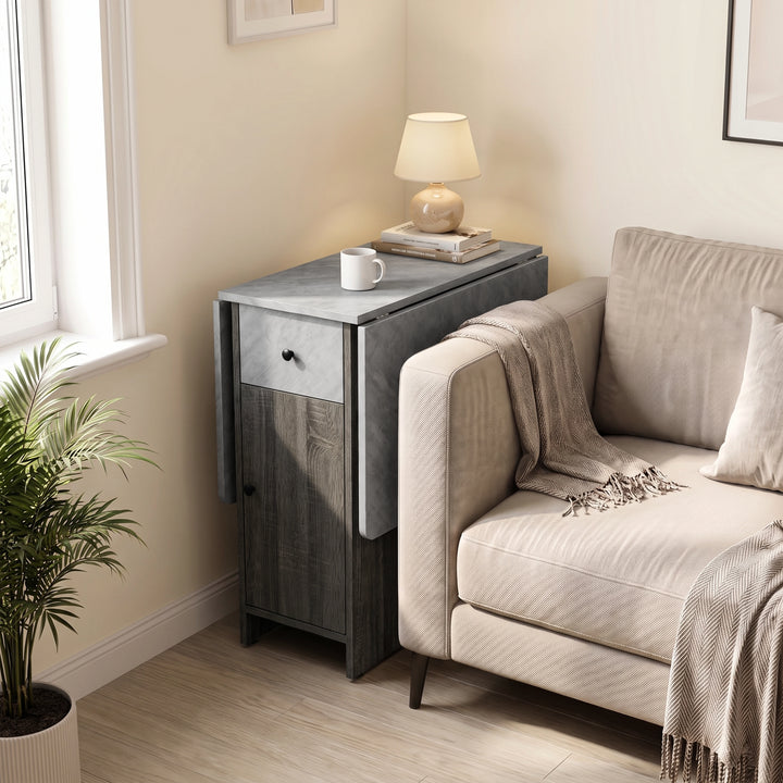 [Grey] Small folding dining table closed beside a sofa and window featuring a marble-effect top with lamp, books and a mug.