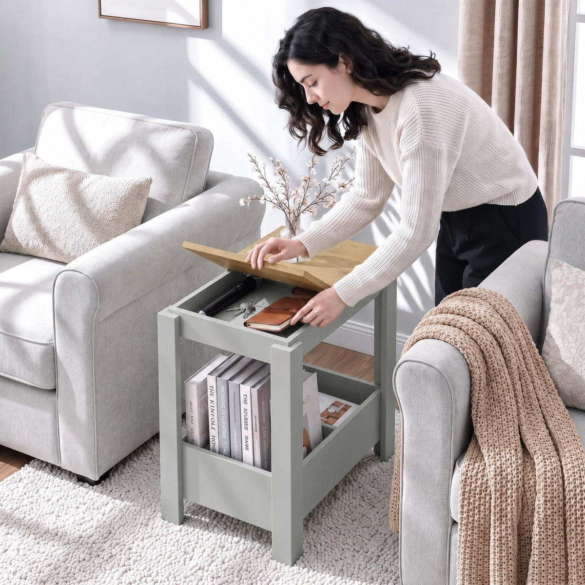 [Grey] A woman lifts a tabletop panel and reaches into the storage compartment beside a sofa, with books below.