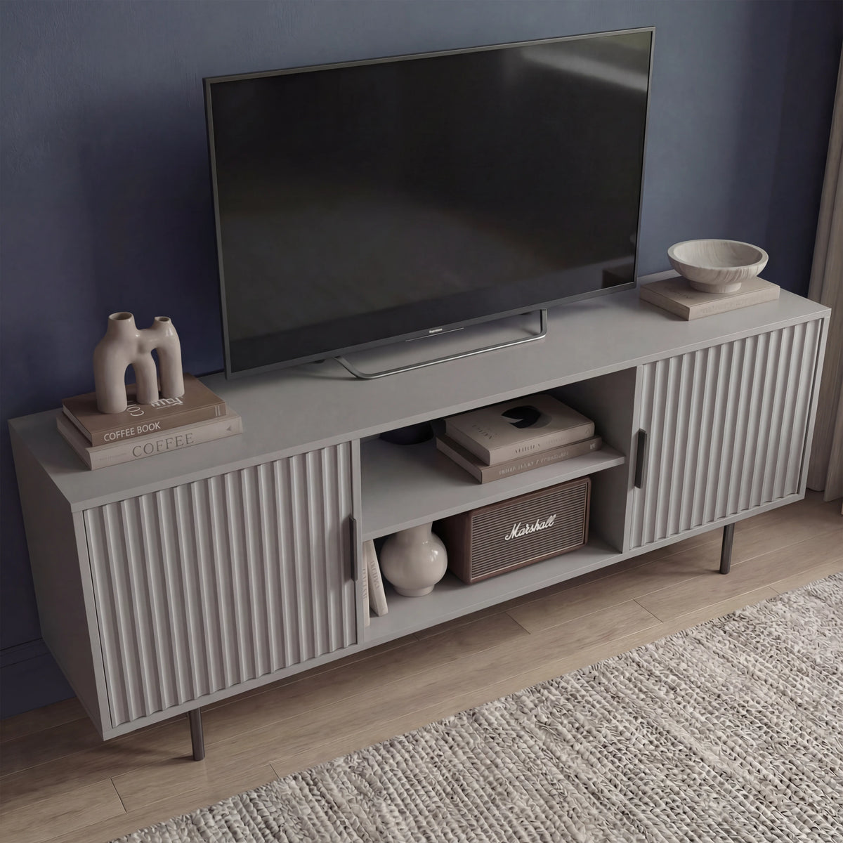 [Grey]  140cm TV unit shot from the left, ribbed door fronts and slim legs, vase plus stacked books on the cabinet top