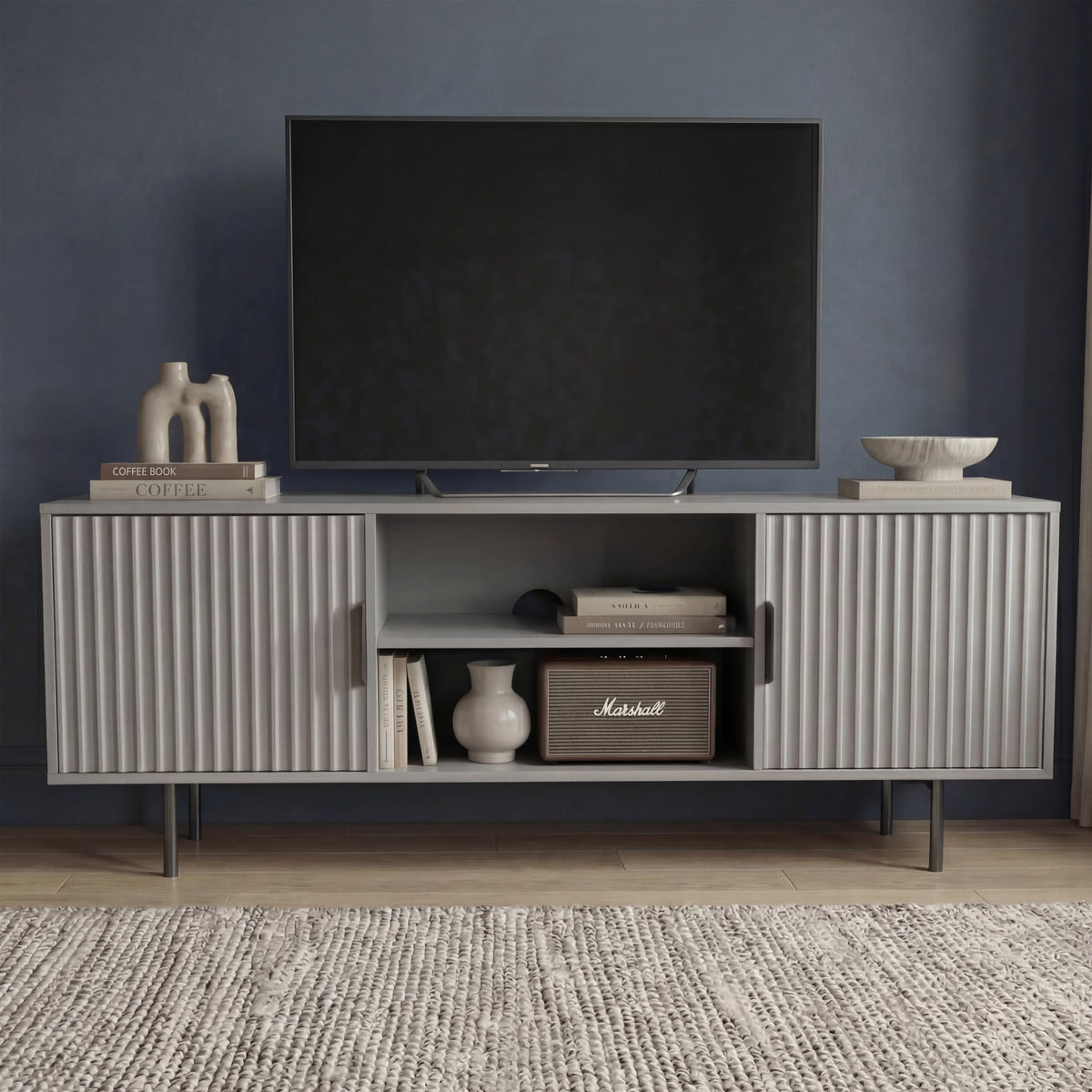 [Grey]  Front view of grey Flutrina 140cm TV unit, two ribbed doors closed and open centre showing books and Marshall speaker