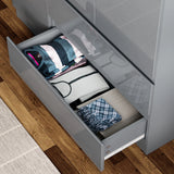 [Grey] Close-up of open bottom drawer of grey high gloss wardrobe with neatly folded clothes and accessories