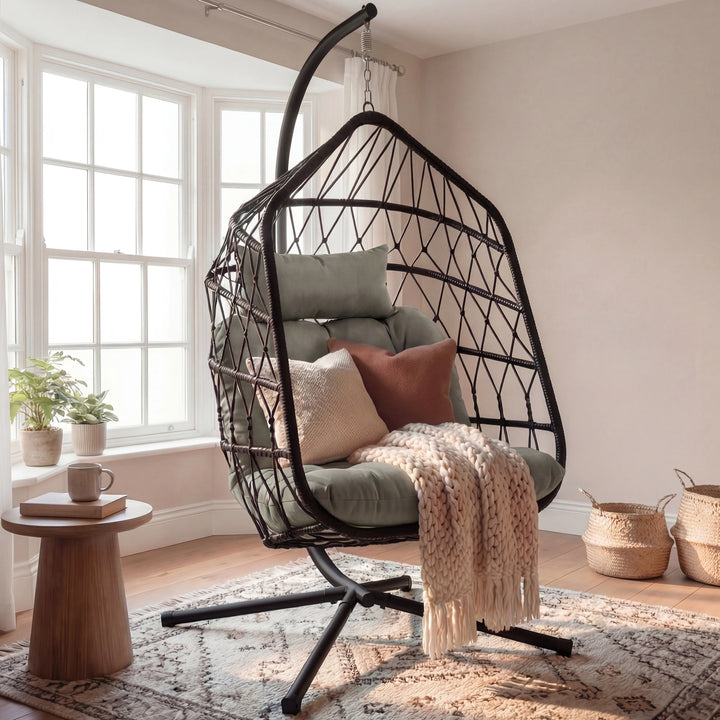 [Black] Black hanging egg chair beside round wooden side table with potted plant and woven baskets in cream painted room