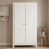 [White] wardrobe with wooden top in a room with a stool and plant