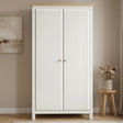 [White] wardrobe with wooden top in a room with a stool and plant