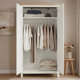 [White] Open wardrobe with clothes and pillows in a room with a wooden stool and plant