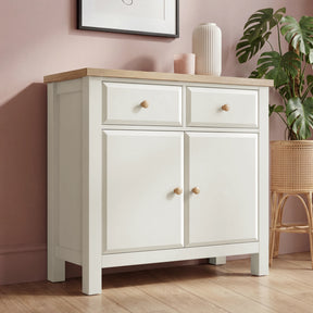 [White] cabinet with wooden top in a room with pink walls and a plant