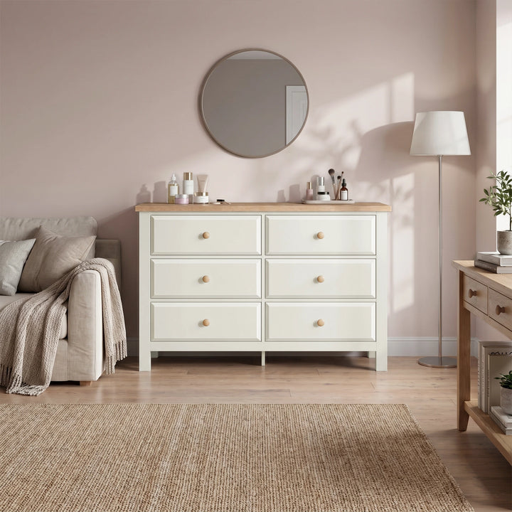 [White] dresser with wooden top in a bedroom setting with a mirror and lamp