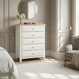 [White] Haven 5-drawer tall chest in a bedroom setting with round mirror and soft furnishings in the background