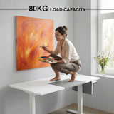 [160cm x 70cm] Strength view of 160x70cm white electric standing desk: adult crouching on top, 80kg load rating