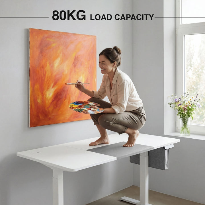[160cm x 70cm] Strength view of 160x70cm white electric standing desk: adult crouching on top, 80kg load rating