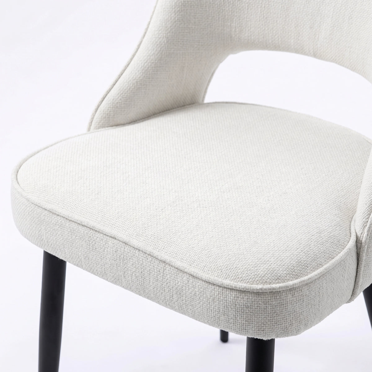 [Cream | Tinted] Close-up of the 4 seater Kyvon cream upholstered fabric comfy chair seat with black metal legs