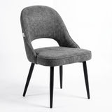 [Grey | Tinted] Kyvon grey upholstered fabric comfy dining chair angled view with black metal legs