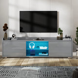[Grey] grey high gloss TV unit below wall TV with blue LED-lit central shelves displaying headphones