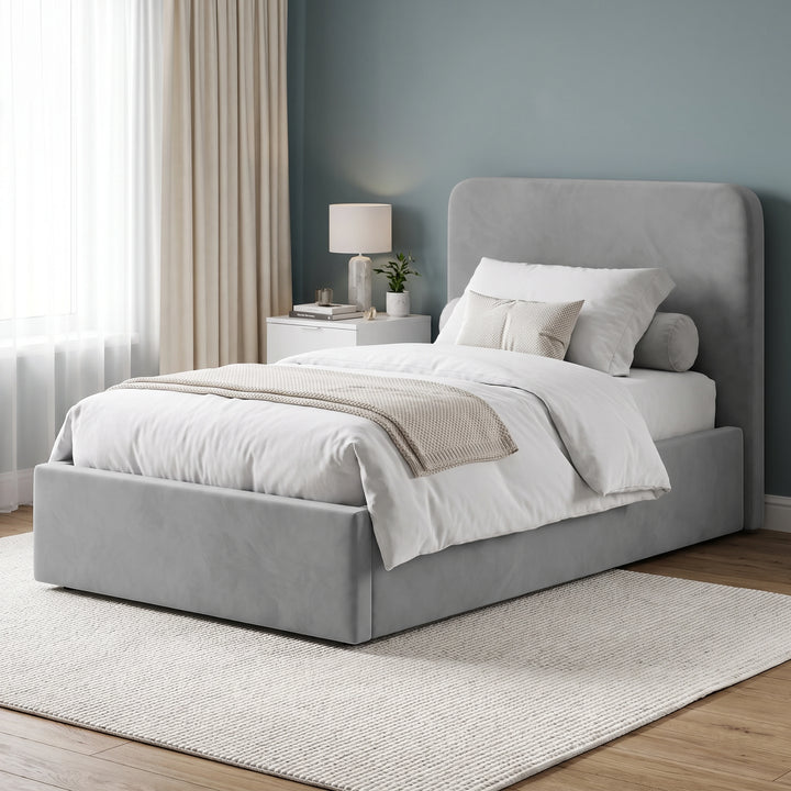 [Light Grey | Small Double] velvet upholstered bed frame with a tall headboard, shown in a styled bedroom setting with white bedding, a beige throw blanket, a nightstand, and a blue-gray wall.
