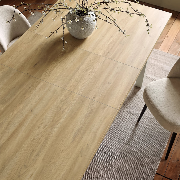 [140cm | Light Oak] 180cm extended Hartley dining table top with 40cm centre leaf, light-oak grain, cream chairs and blossom vase.