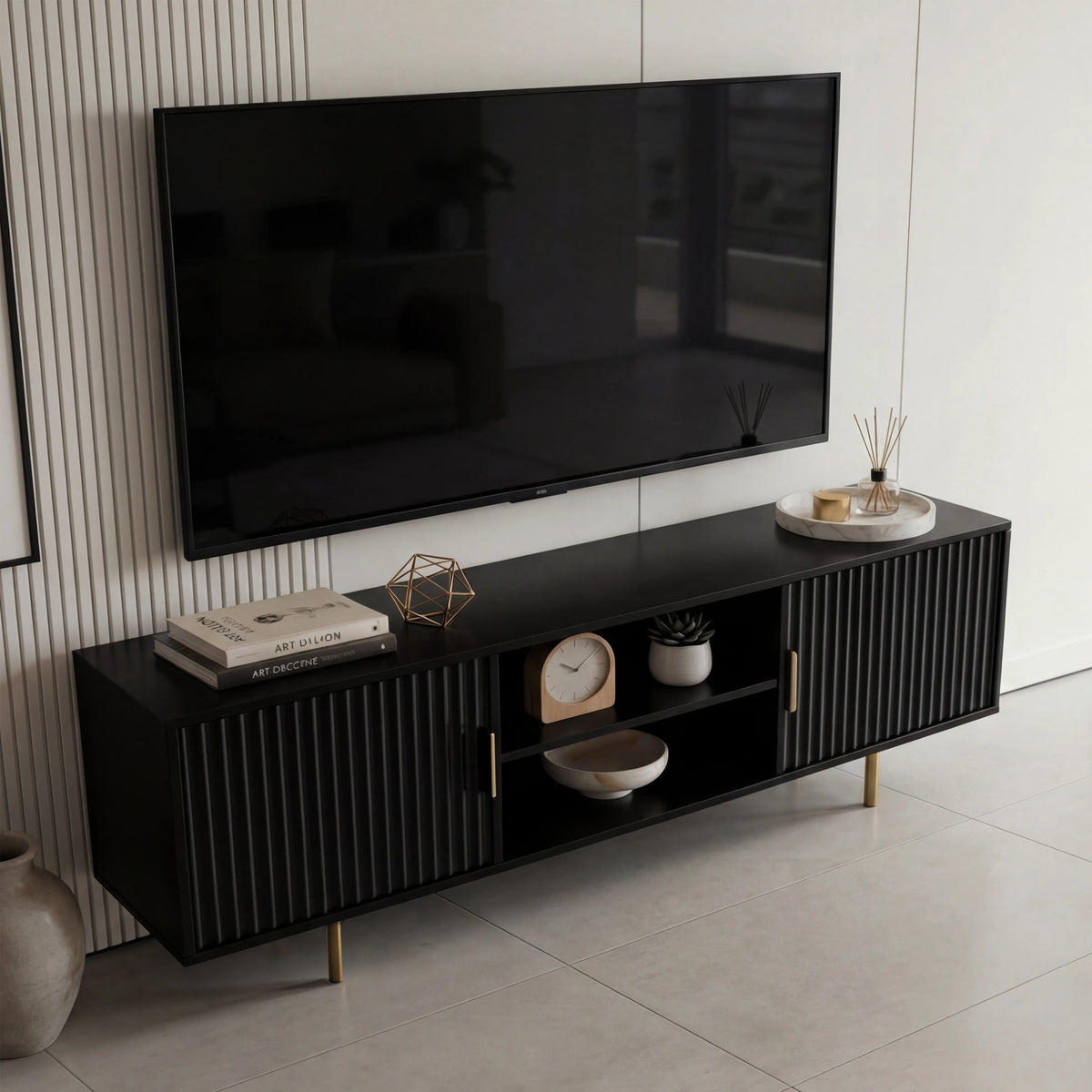 [Black] Brass leg pair detail under black Flutrina TV unit with fluted door grooves visible above the legs.