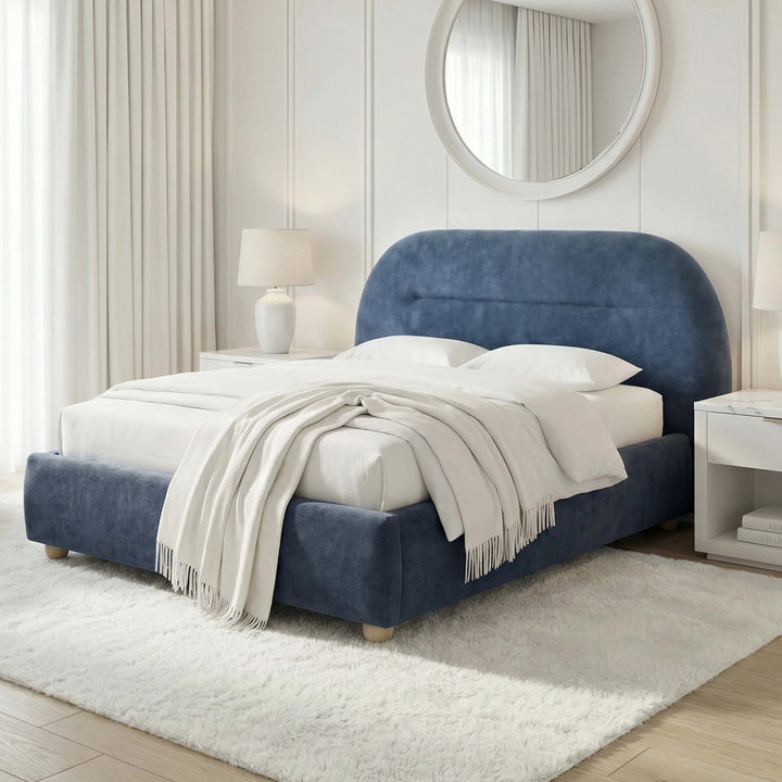 [Blue | Double] Angled view of upholstered bed frame revealing headboard depth beside floating nightstand and ceramic lamp
