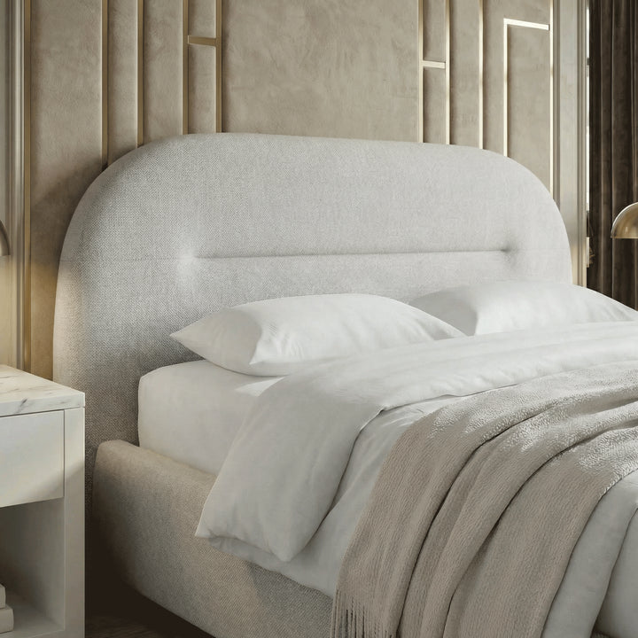[Grey | Double] Close crop of upholstered headboard with channel seam against ornate gold moulding panels and brass lamp glow