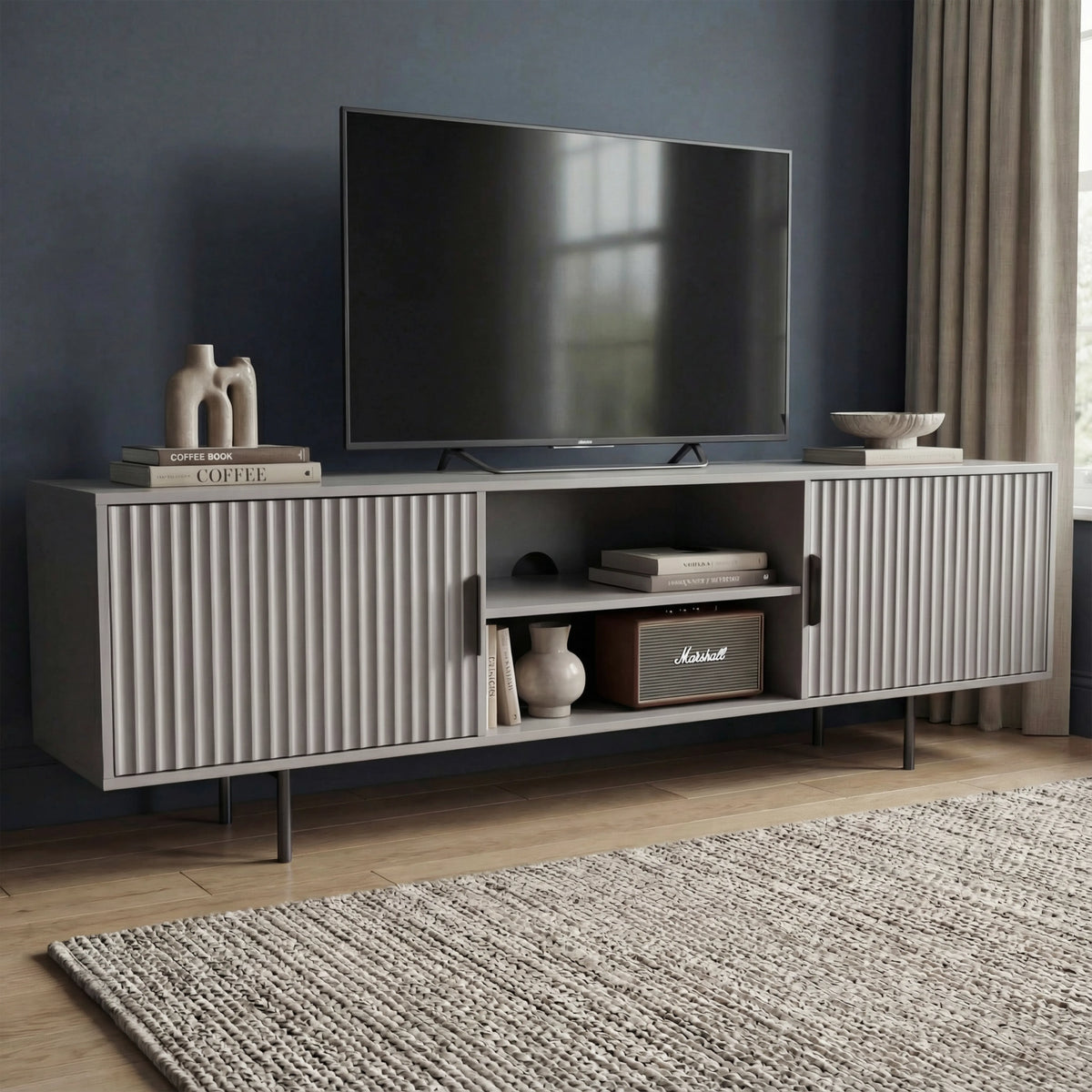 [Grey] Angled grey 180cm TV unit with mounted TV on navy wall, Marshall speaker and ceramic vase on central open shelf.