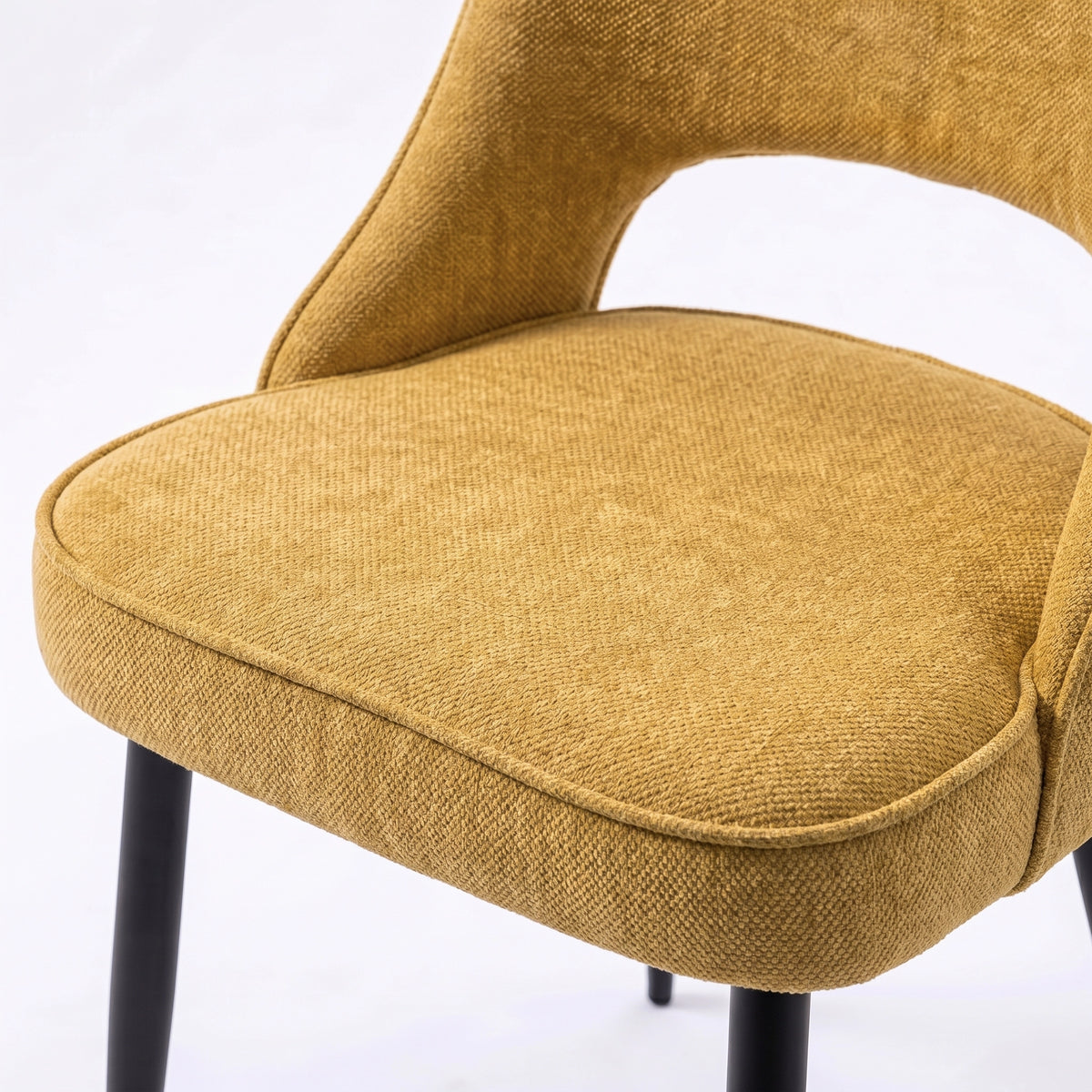 [Mustard | Set of 4] Comfy dining chair close-up of padded seat, piped edge, curved open back and black metal legs.