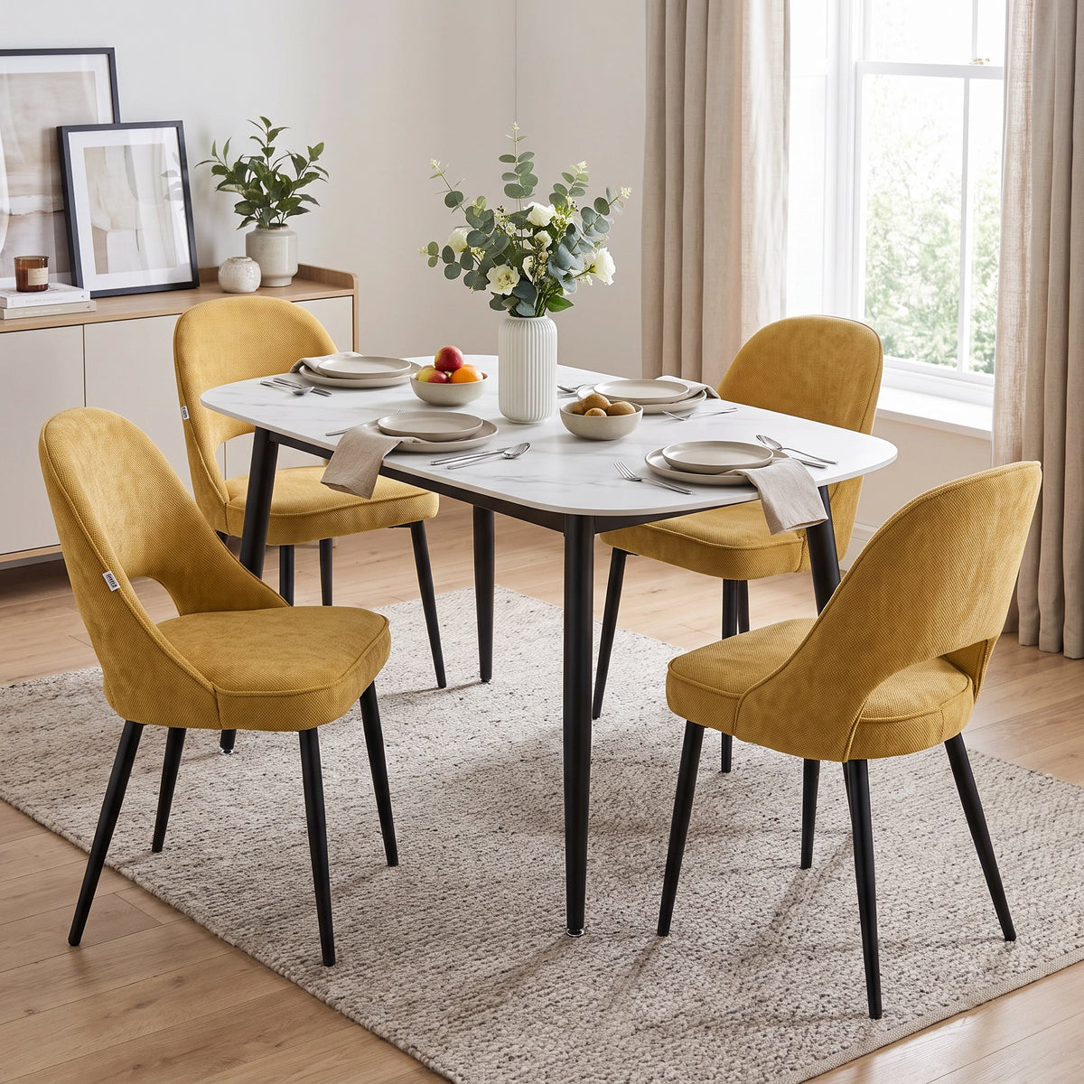 [Mustard | Set of 2] Two pairs of the comfy dining chairs at a white marble-effect table styled with fruit and flowers.