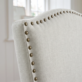 [Beige | Set of 2] Close-up of curved high back with fabric upholstery and bronze nailhead trim