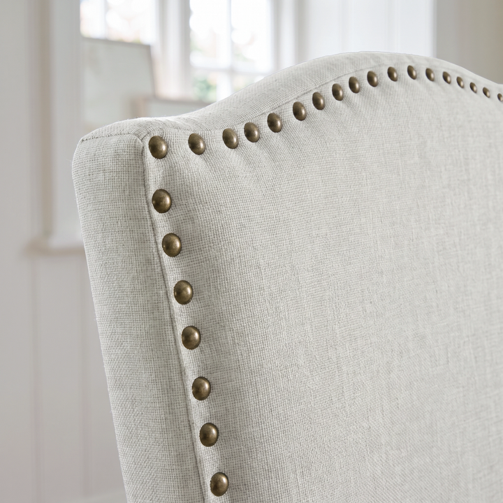 [Beige | Set of 4] Close-up of curved high back with fabric upholstery and bronze nailhead trim