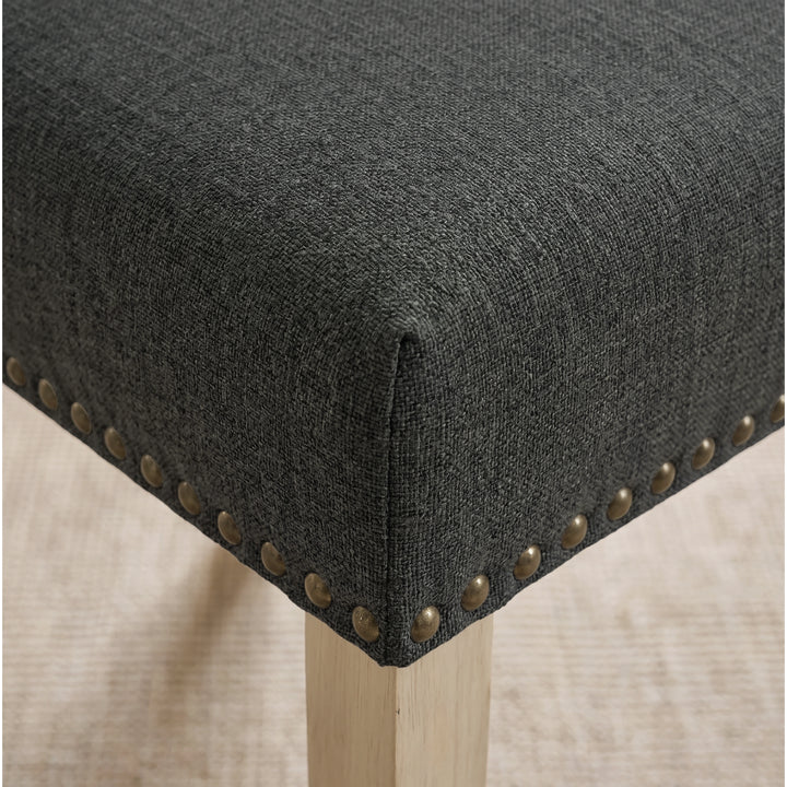 [Dark Grey | Set of 4] Close-up of fabric seat, bronze nailhead trim and light wooden leg on the dining chair