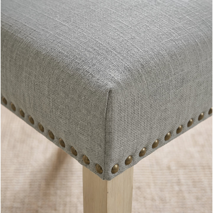[Light Grey | Set of 4] Close-up of fabric seat, bronze nailhead trim and light wooden leg on the dining chair