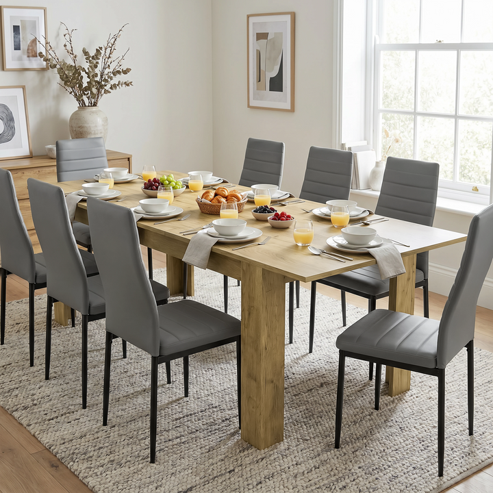 [Oak] Extended oak-effect dining table for 6-8 at breakfast; eight grey chairs surround its thick square legs.
