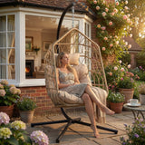 [Natural] Natural rattan egg chair on stone patio with seated woman and potted hydrangeas in summer garden