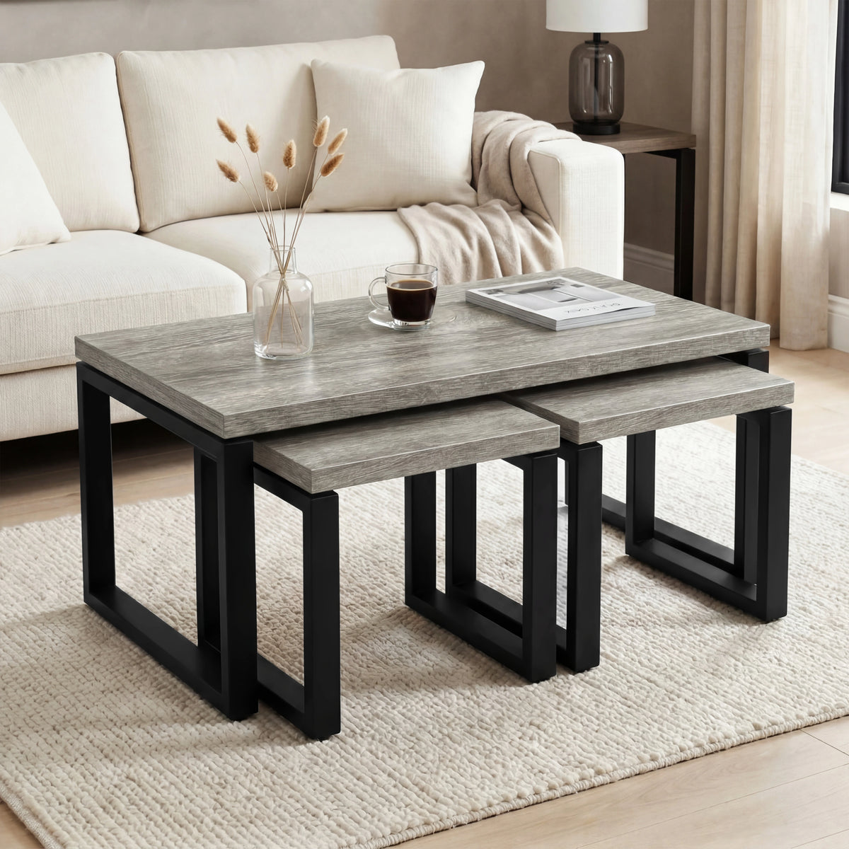 [Grey] Nestline coffee table set beside a cream sofa, with soft cushions, flowers, and nesting side tables pulled out