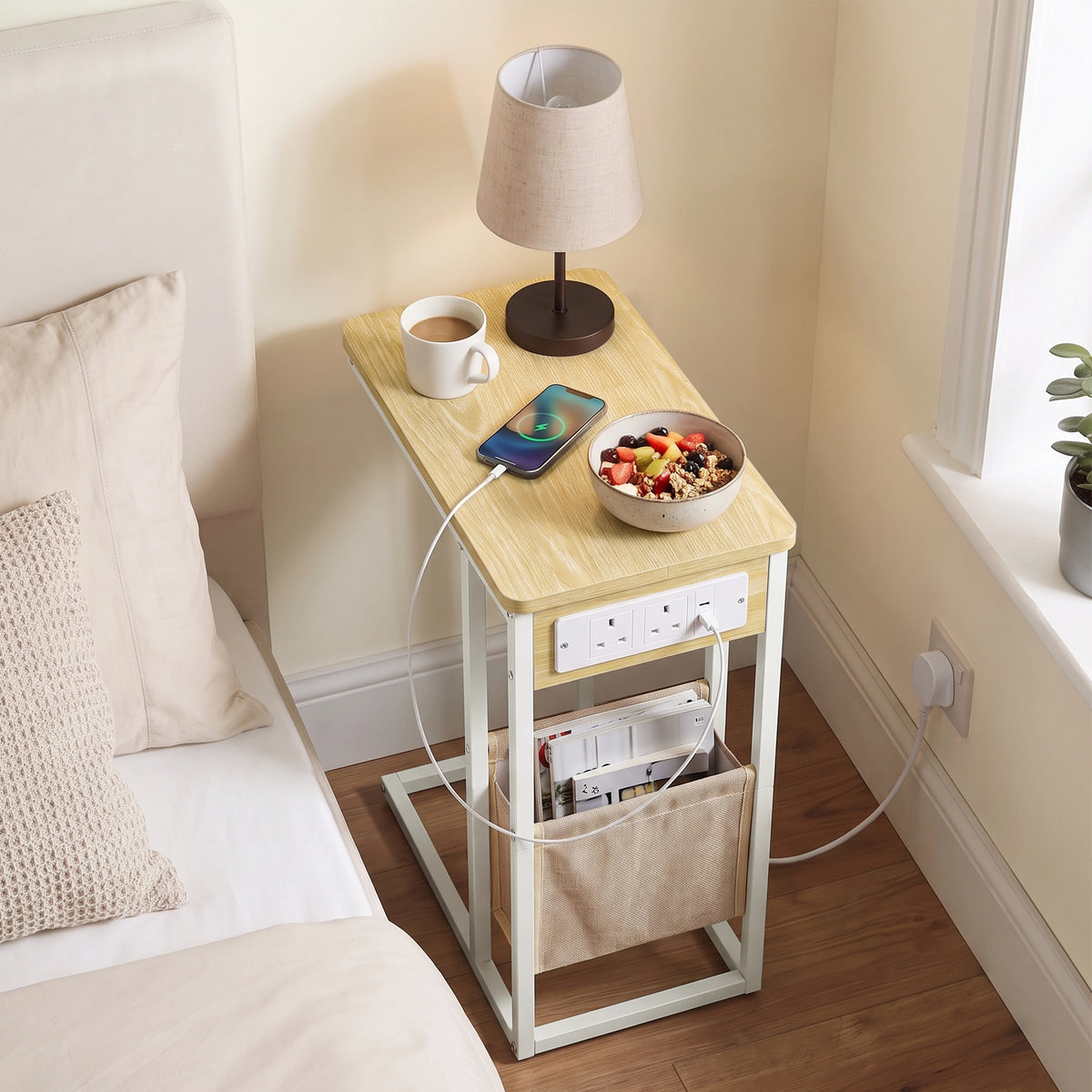 [Oak] Top view of C-shaped side table with oak-effect top, charging cable, phone and pouch used as bed side table