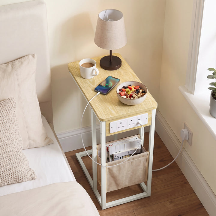 [Oak] Top view of C-shaped side table with oak-effect top, charging cable, phone and pouch used as bed side table
