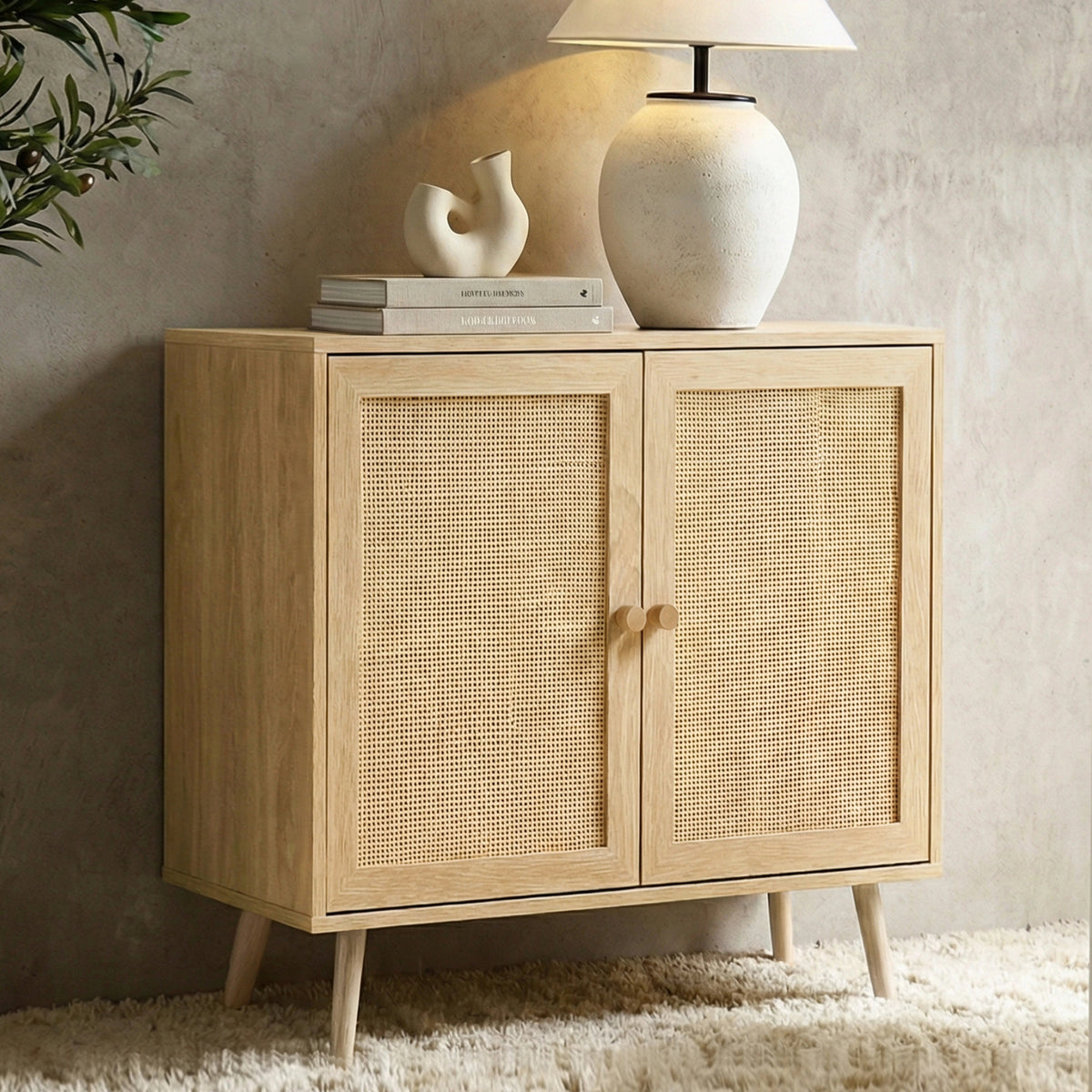 [Oak Effect] Wovena sideboard slight angle view, two rattan doors closed, ceramic lamp and books on top