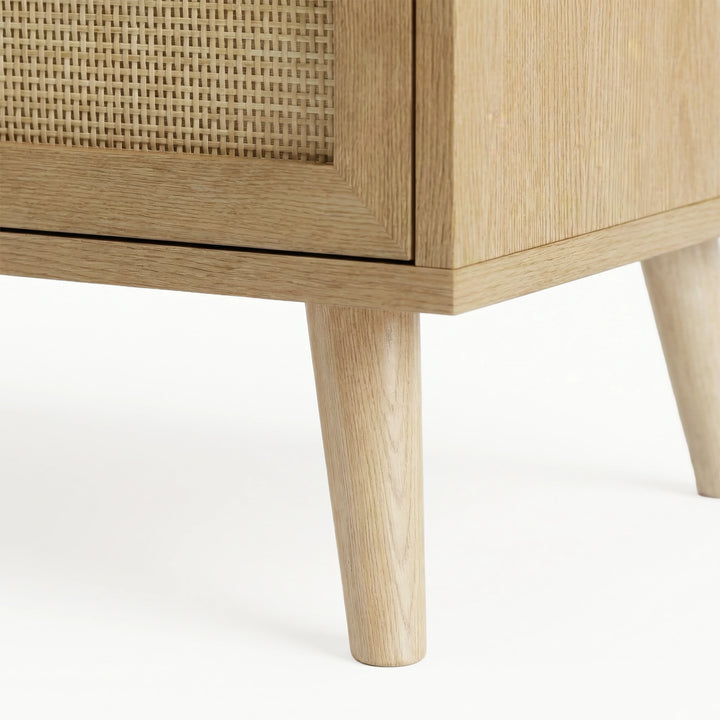 [Oak] Wovena close-up of natural oak tapered leg showing smooth grain texture and rattan panel edge on white