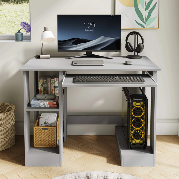 [Grey] Front view of grey computer desk styled with lamp at left, headphones at right and gaming PC tower below