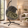 [Grey] woven hanging egg chair with an olive green cushion sits in a modern living room setting with a black metal stand, next to a beige sofa and a floor lamp.