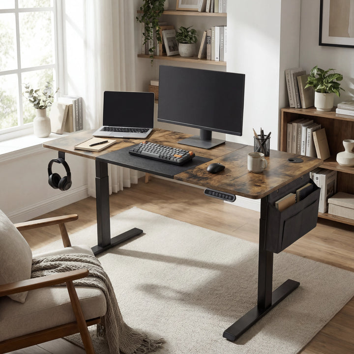 [110cm x 60cm] Lifestyle shot of the 110cm rustic adjustable desk; laptop and monitor on top, armchair and rug in foreground