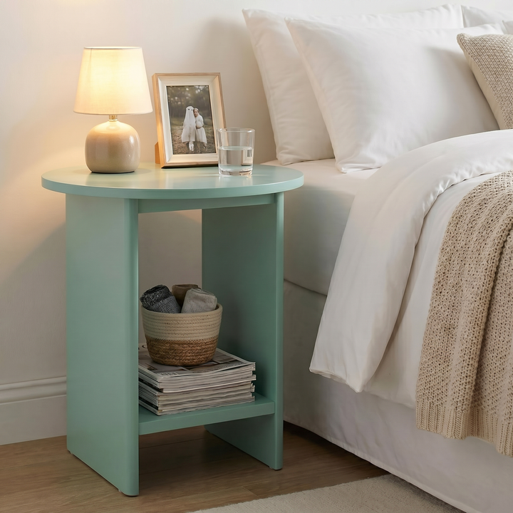 [Sage Green] Small Round Side Table with Shelf Living Room used as bedside table beside white bed with lamp and photo frame on top and wicker basket on lower shelf