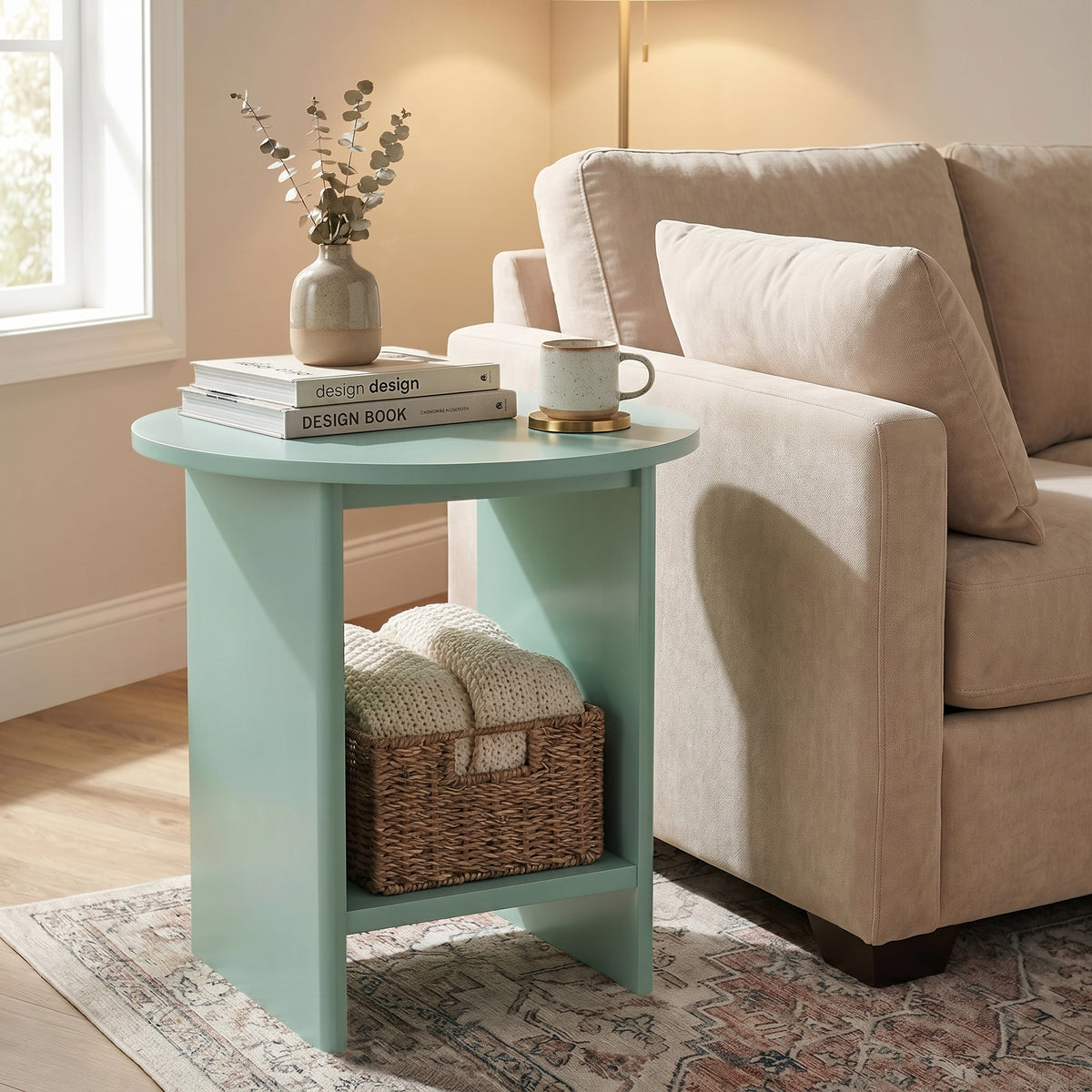 [Sage Green] Small Round Side Table with Shelf Living Room positioned beside a cream sofa with books and mug on top and wicker basket on lower shelf