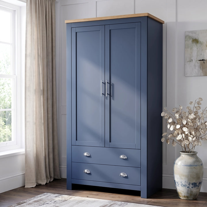 [Blue] two-door wardrobe with a light wood top and silver handles, set in a bright room next to a window with beige curtains and a decorative vase.