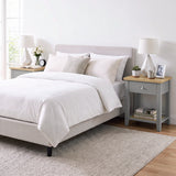 [Grey] Wide bedroom scene showing the bedside table next to a bed with books on the lower shelf